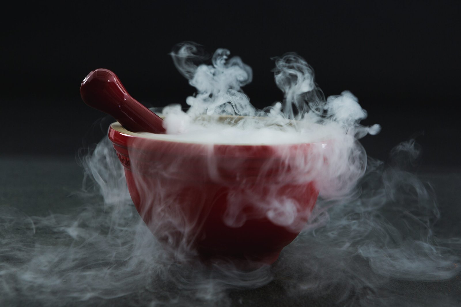 Close-up of dry ice smoke in bowl on black background