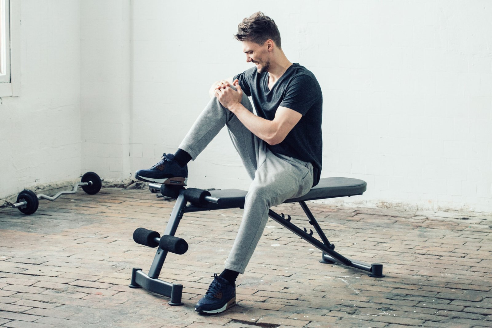 Man sport pain. Handsome guy in sport gym back pain and led. Studio shot.