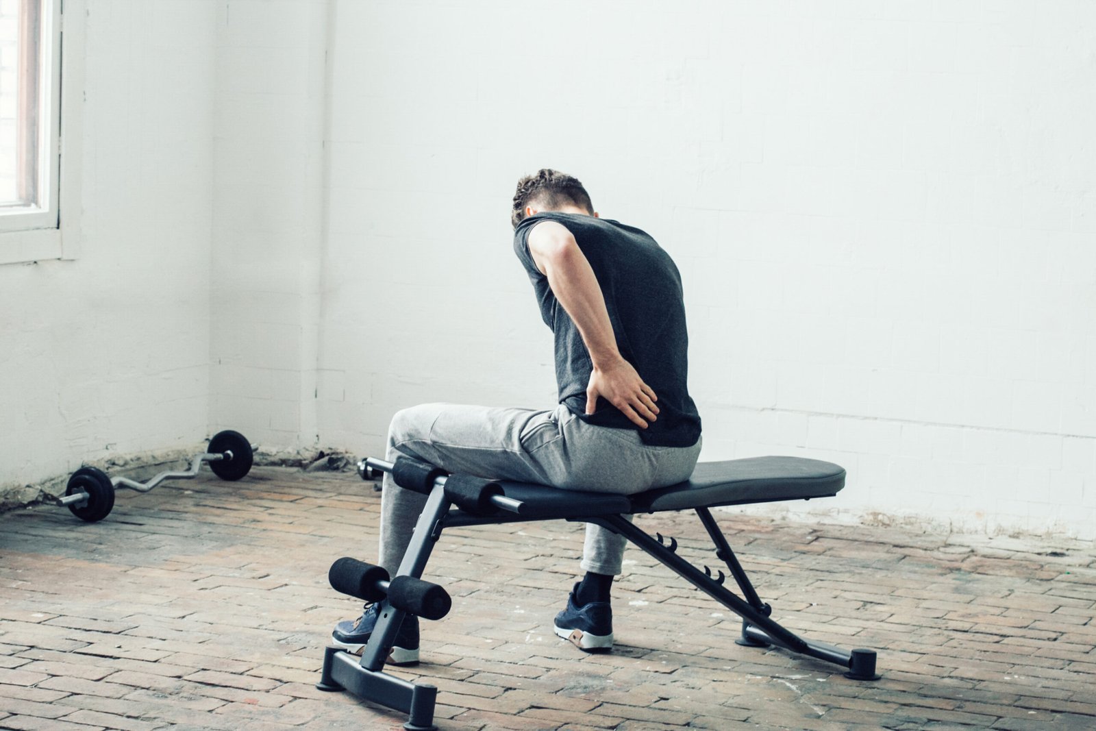 Man sport pain. Handsome guy in sport gym back pain and led. Studio shot.